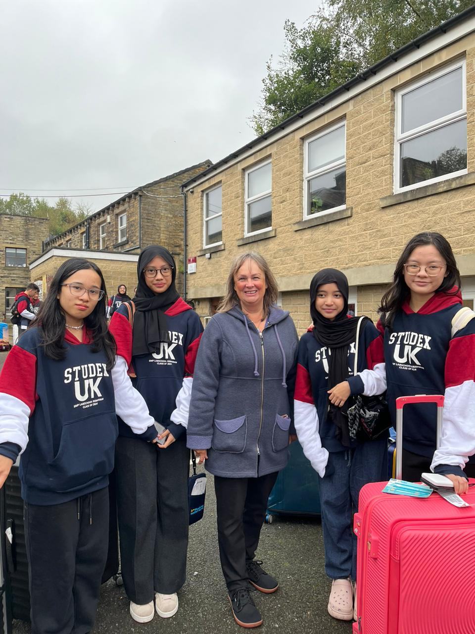 Students with their luggage arriving at school with a member of staff